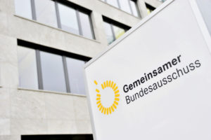 Schild des G-BAs vor Gebäude. Darauf das Logos sowie der Text: "Gemeinsamer Bundesauschuss" Gemeinsamer ist dabei fett geschrieben.