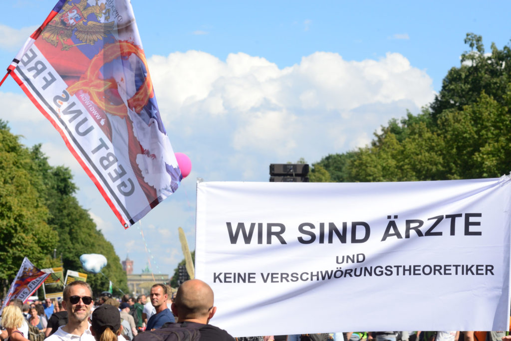 Demonstranten unter blauem Himmel mit großem Banner in der Hand und Fahne schwenkend.