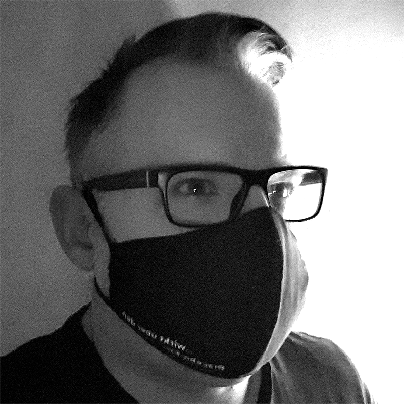 Mann mit Brille und Schutzmaske aus Stoff über Mund und Nase.