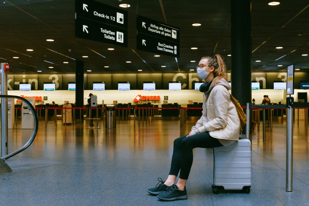 Frau mit Corona-Maske sitzt am Flughafen.