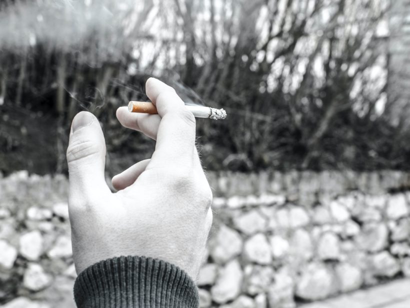 Hand hält eine brennende Zigarette