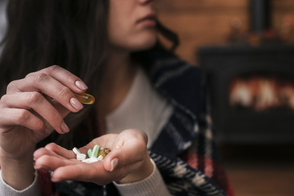 Nahaufnahme Frau mit diversen Kapseln und Tabletten in ihrer Hand